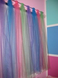 there are many colorful streamers hanging from the wall in this room with pink, blue and green walls