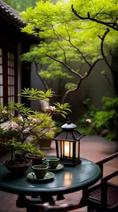 a table with two cups on it next to a lantern and some trees in the background