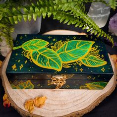 a green and yellow painted box sitting on top of a tree stump next to a plant