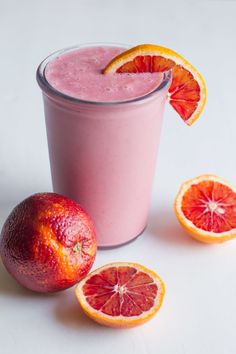 there is a pink smoothie with blood oranges on the side