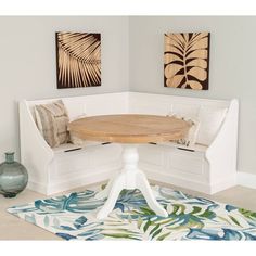 a wooden table sitting on top of a white bench next to a vase and painting