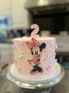 a pink and white cake with minnie mouse on it