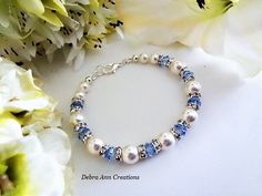 a bracelet with blue and white beads is sitting next to some flowers on a table