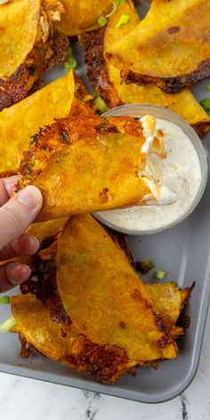 a person dipping some food into a bowl with ranch dressing on the side and another hand reaching for it