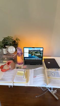 an open laptop computer sitting on top of a desk next to books and other items