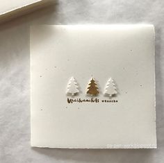 two small christmas trees are sitting on top of a piece of paper