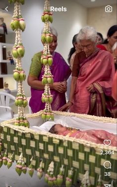 an older woman standing next to a baby in a crib