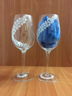 two wine glasses sitting on top of a wooden table covered in blue flowers and leaves