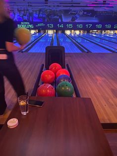 a bowling alley with lanes full of bowling balls and drinking glasses on the sidelines