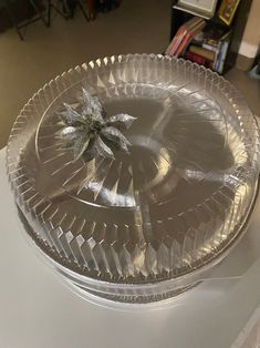 a clear glass dish with a flower on the top and some silver foil around it