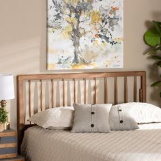 a bed with white sheets and pillows next to a painting on the wall above it