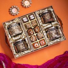 an open gift box filled with assorted chocolates on top of a pink blanket