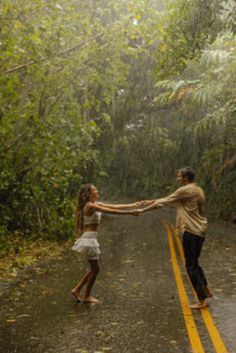 two people holding hands while walking down the road in the rain