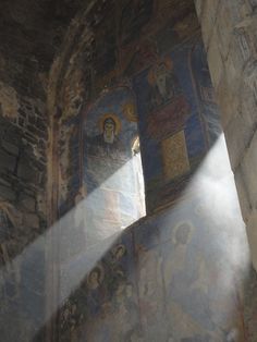 sunlight shining through the window into an old building with paintings on it's walls