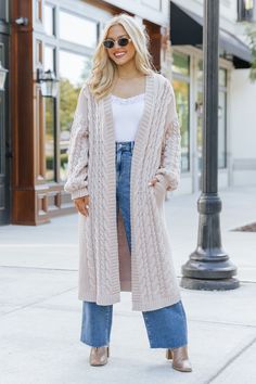 Wrap yourself in cozy comfort with our Chunky Cable Knit Duster Cardigan in a soft light beige hue! Designed for the free-spirited and effortlessly chic, this longline cardigan is the perfect layering piece for any boho-inspired look. Crafted from a chunky cabe knit material, this duster cardigan offers maximum coziness, giving you that wrapped-in-a-blanket feel with a stylish twist. Perfect for layering during those crisp fall mornings or cool evenings, this cardigan is an essential for any boh Long Cream Cardigan For Winter, Cream Sweater Coat For Winter, Trendy Cream Soft Knit Outerwear, Beige Long Knit Outerwear, Long Beige Knit Outerwear, Cozy Long Spring Outerwear, Beige Long Soft Knit Sweater Coat, Long Beige Soft Knit Sweater Coat, Long Beige Soft Knit Outerwear