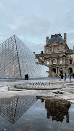 people are standing in front of the glass pyramid