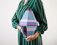 a woman is holding an origami object in her hands and wearing a green striped dress