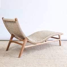 a woven chaise lounge chair sitting on top of a carpeted floor next to a white wall