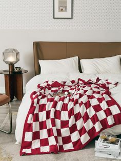 a red and white checkered blanket is laying on the floor next to a bed