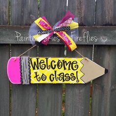 a welcome to class sign hanging on a fence next to a wooden board with the words welcome to class