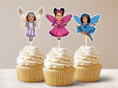 three cupcakes with little fairy toppers on them