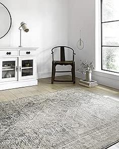 a living room with white furniture and a large rug on the floor in front of a window