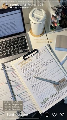 an open laptop computer sitting on top of a desk next to a paper and pen