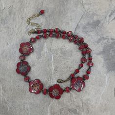 "This is a very striking 3 piece set.  It is made with lovely glass beads made in the Czech Republic.  They are dark red with charcoal finish and bronze wash.  These beads are A+ quality.  Photos show short length and extended length.  Necklace is 18\" long and a 3\" extender chain is attached so you can adjust it to your neckline.  Set is accented with antique brass beads, lobster claw clasp, toggle clasp, ear wires and chain.  Matching bracelet is 8\" long and is finished with a JBB leaf toggl Dark Red Jewelry, Red Jewelry Set, Red Flower Necklace, Flowers Dark, Flowers Red, Red Jewelry, Glass Flowers, Red Flower, Czech Beads