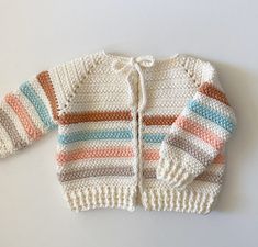 a crocheted sweater with multicolored stripes on the front and back, sitting on a white surface