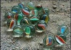 several glass marbles sitting on the ground next to each other