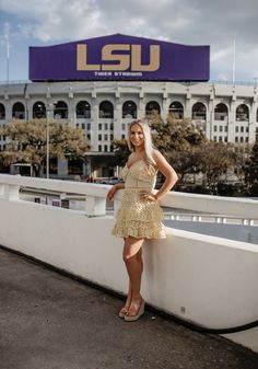 a woman standing on the side of a bridge in front of a lsu stadium sign