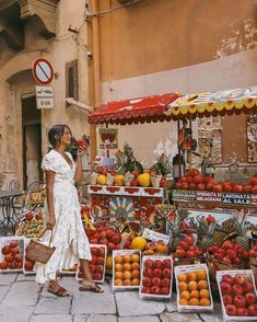 a woman standing in front of a fruit stand