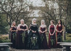 a group of women standing next to each other in long dresses and holding bouquets