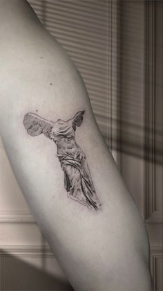 a woman's arm with a tattoo on it that has the statue of jesus