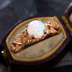 an opalite and diamond ring in a wooden box with gold trimmings