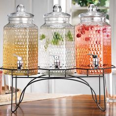 three glass jars with soap dispensers sitting on a metal stand next to each other