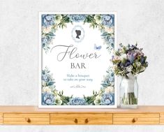 a flower bar sign sitting on top of a wooden table next to a vase filled with flowers