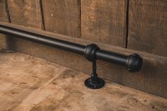 an iron pipe is mounted to the side of a wooden wall with a black handle