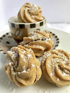 some cookies are sitting on a plate next to a cup and saucer with powdered sugar