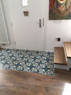 a blue and white rug on the floor in front of a door with a painting hanging above it