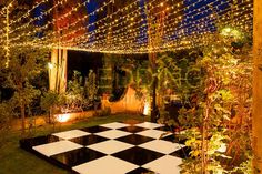 a black and white checkerboard dance floor surrounded by greenery with fairy lights