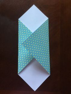 an origami piece with white and green dots on it sitting on top of a wooden table