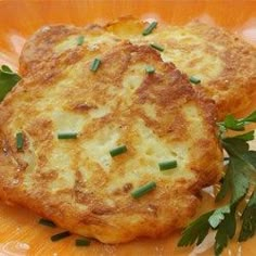 two crab cakes on an orange plate with parsley