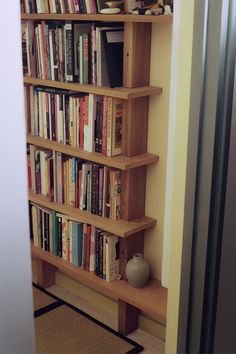 a bookshelf filled with lots of books next to a wall mounted vase and door