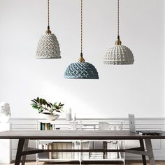 three pendant lights hanging from the ceiling above a table