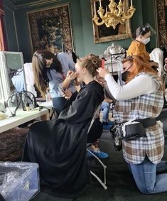 a group of women sitting around each other in front of a table with hair dryers on it