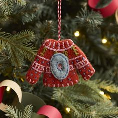 an ornament hanging from a christmas tree decorated with red and blue sweaters