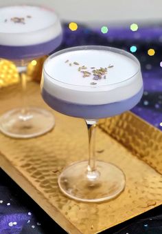 two martinis with lavender garnish sit on a gold tray