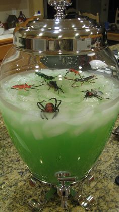 a green liquid in a glass bowl on top of a counter next to a silver lid