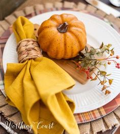 a white plate topped with a pumpkin next to a yellow napkin